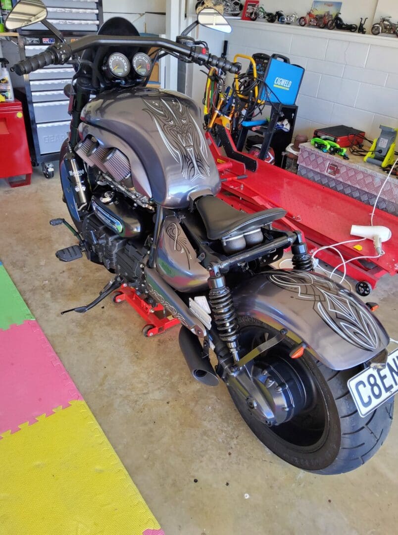 A motorcycle is parked in the garage with its front end removed.