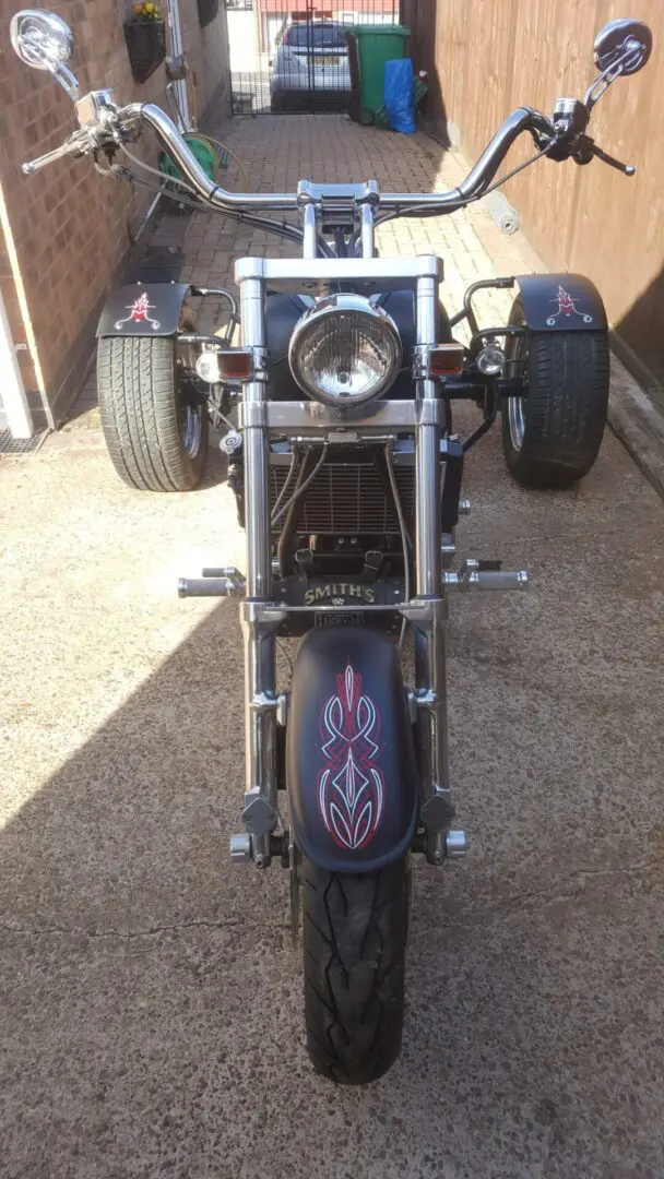 A motorcycle with three wheels parked in the driveway.