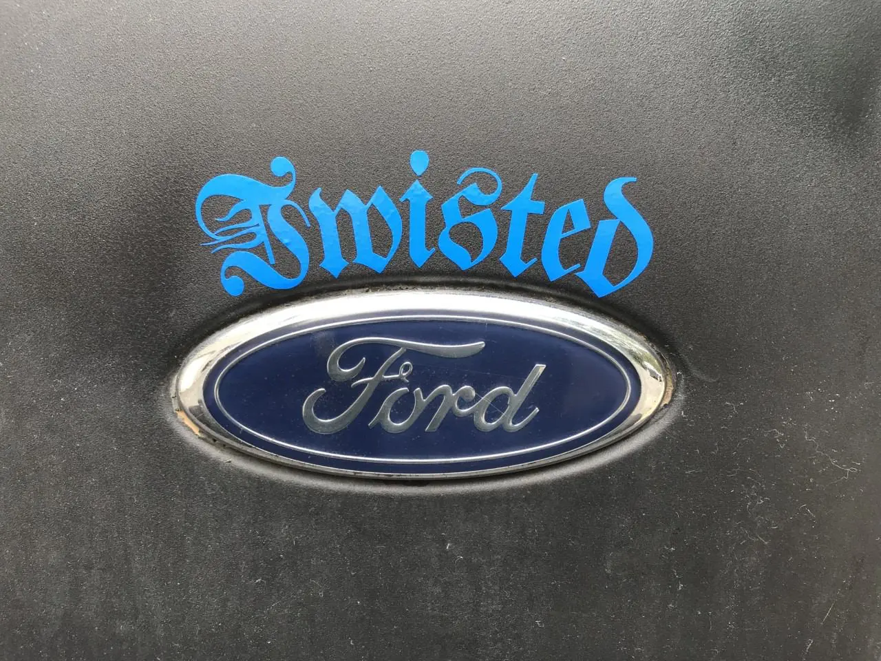 A blue and silver ford logo on the side of a car.