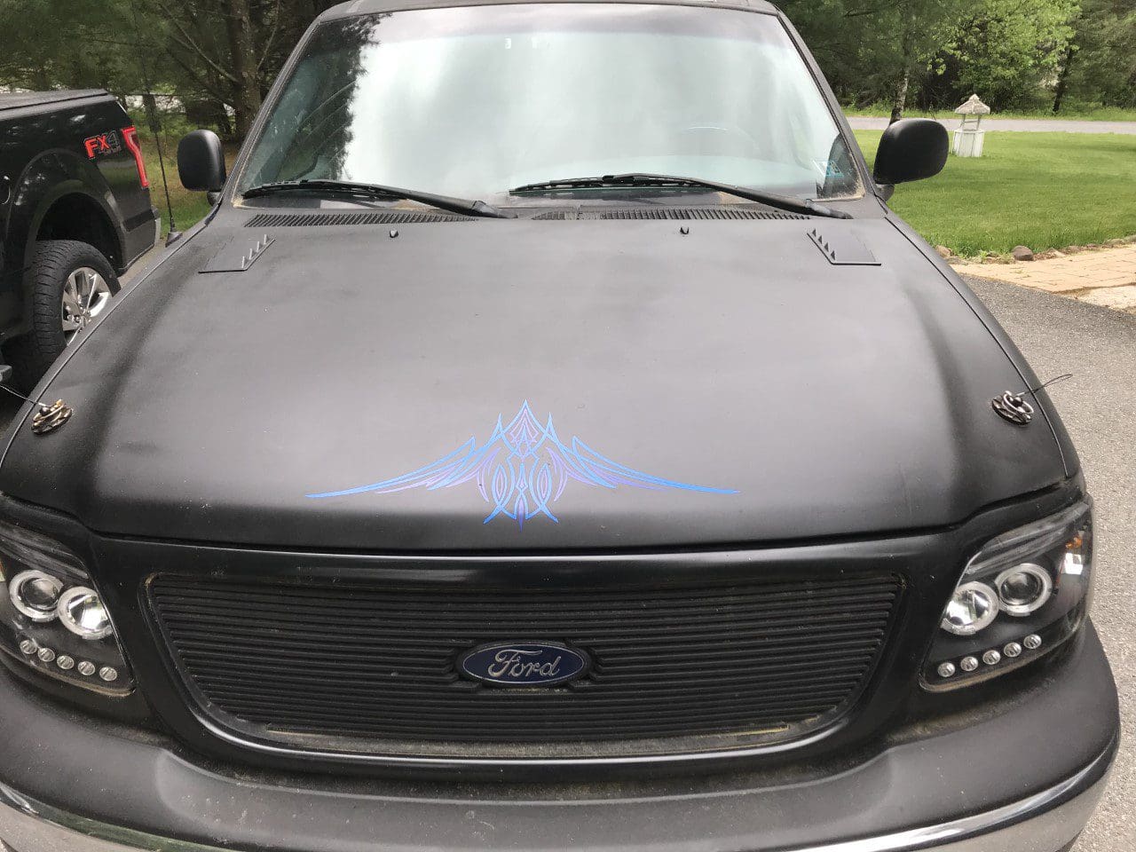 A black truck with blue paint on the hood.