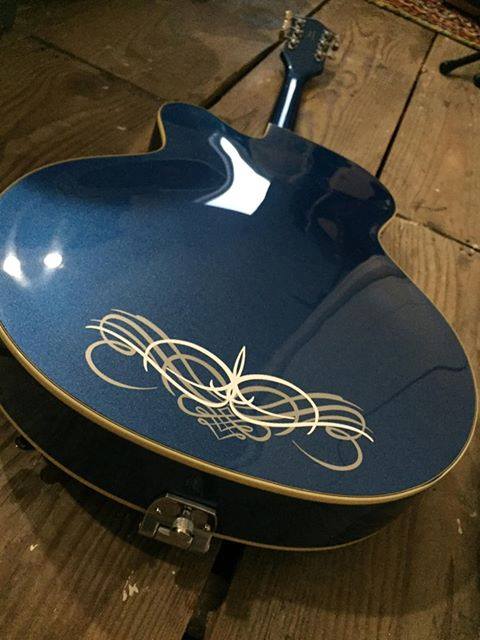 A blue guitar sitting on top of a wooden floor.