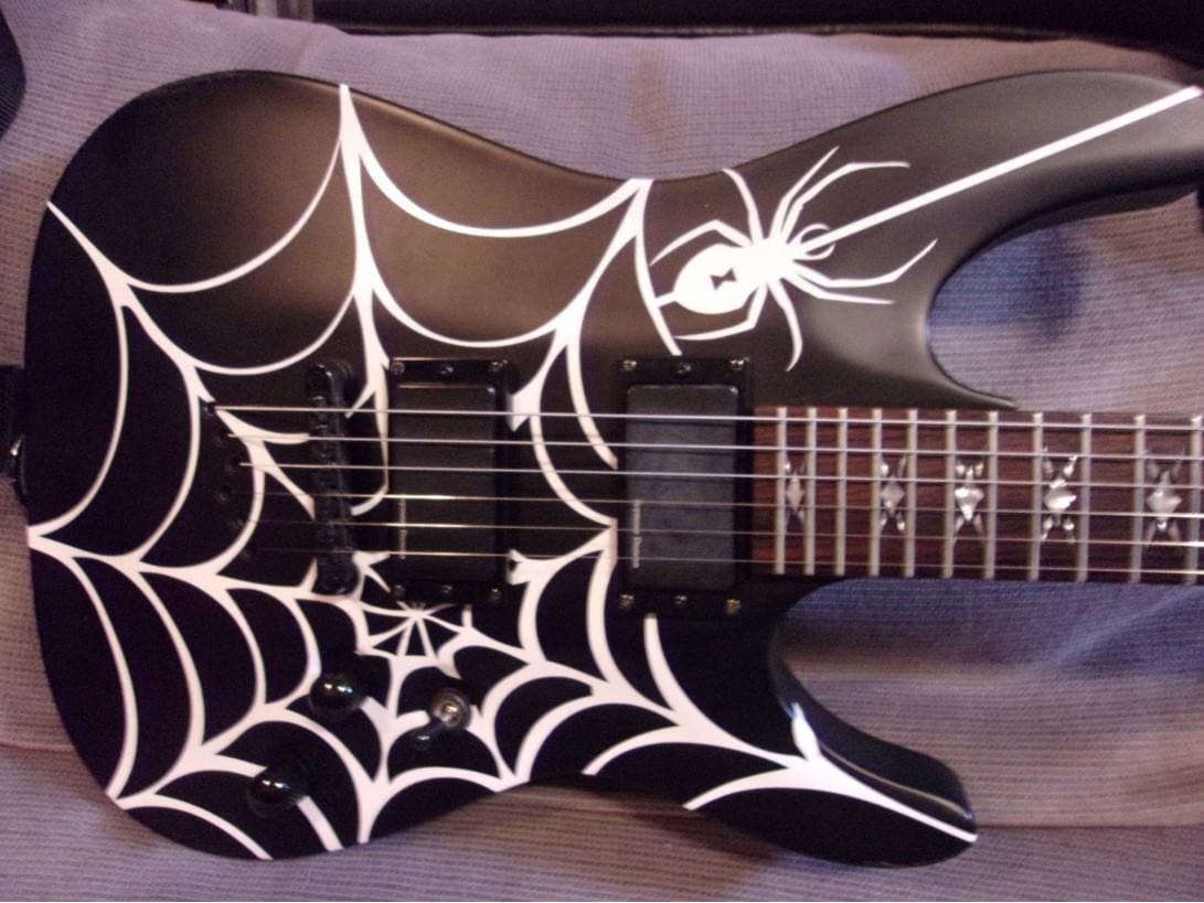 A black and white guitar with spider web design