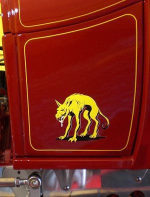 A red refrigerator with yellow and black painting of a dog.